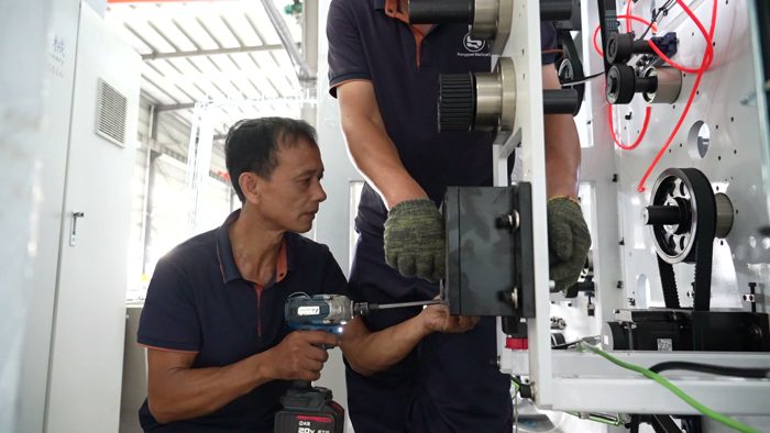 Two technicians fitting a component to production machinery