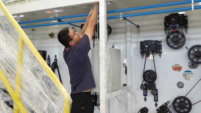 Technician working on an upper section of the machine